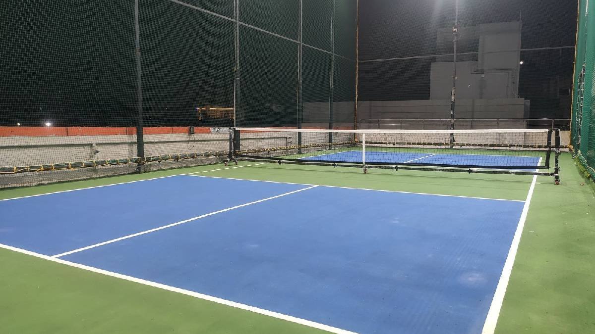 Blue and green cricket court under lights